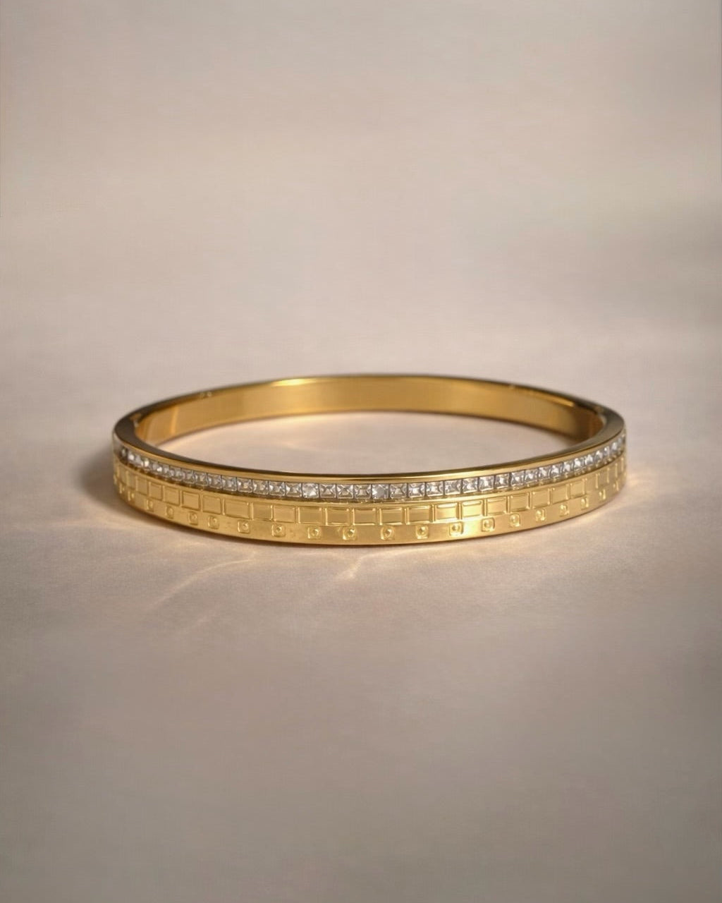 Gold bracelet with diamond accents on a light beige background