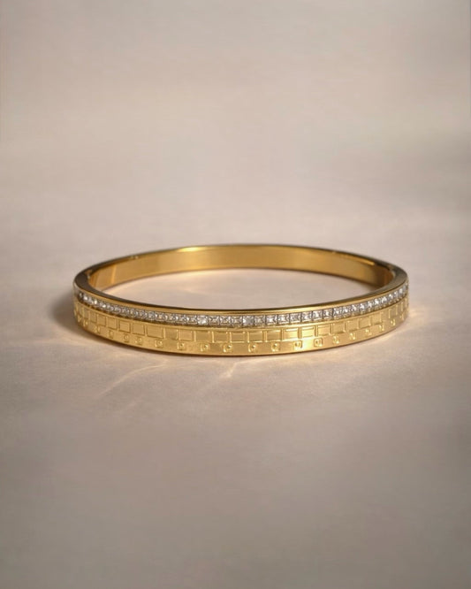 Gold bracelet with diamond accents on a light beige background